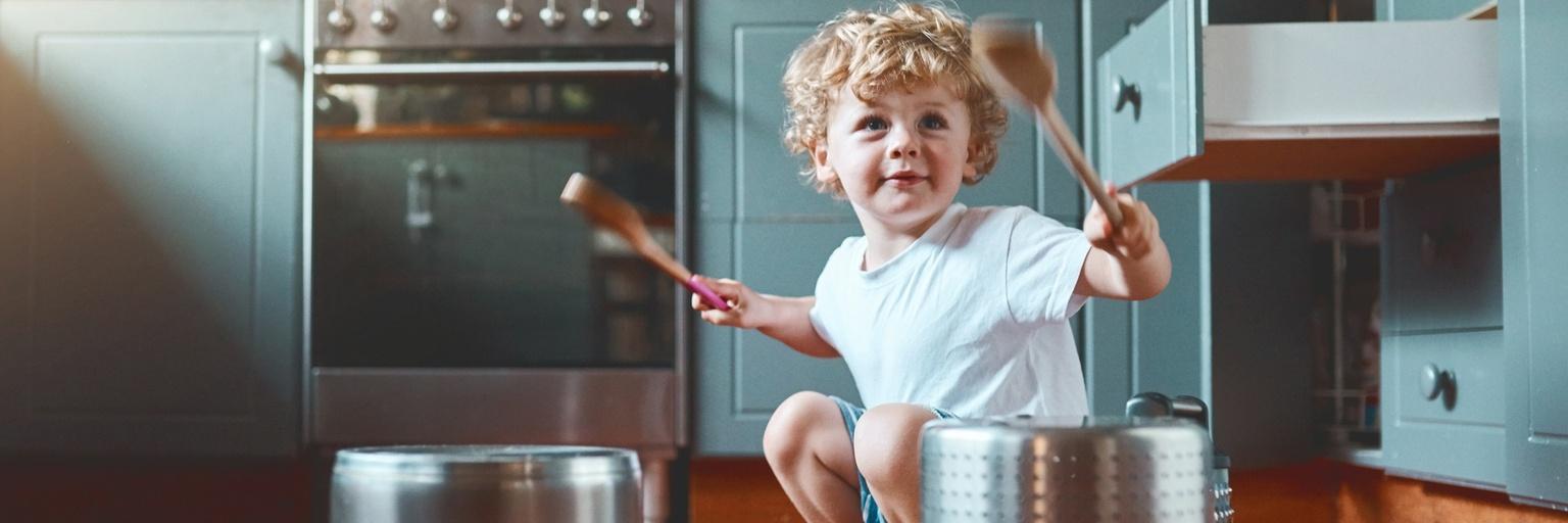 Image of young boy playing drums with kitchen tools.