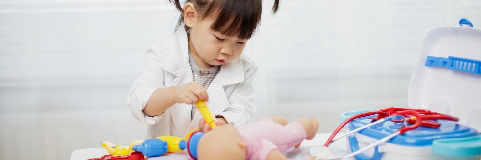 Image of two-year-old girl playing doctor at home.