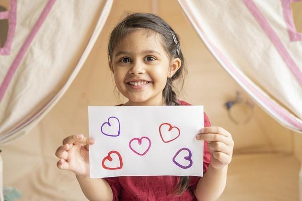 Child showing off heart stamp artwork