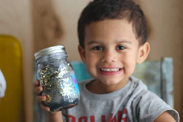 Niño con su proyecto terminado, galaxia en un frasco.