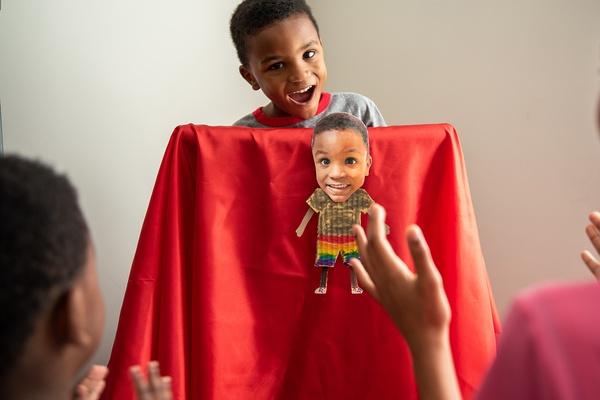 Imagen de un niño realizando una obra teatral con una marioneta de un miembro de la familia.