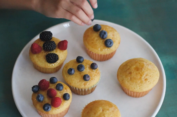 Un niño decorando con frutas los cupcakes de miel.