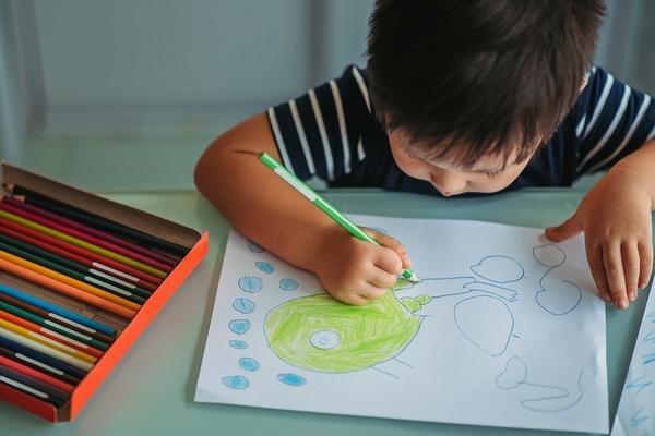 Child drawing a picture with colored pencils.