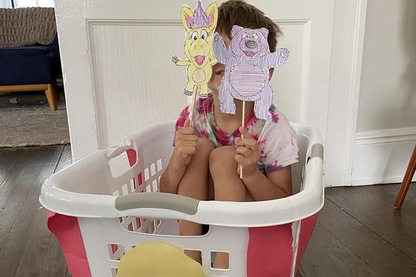 A child sitting in a laundry basket decorated to look like Trolley.