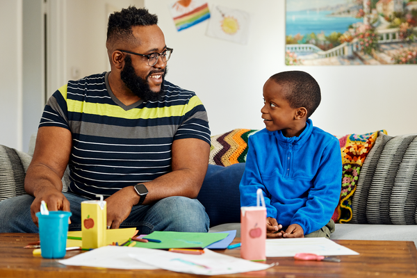 A parent and child smile at each other while exploring cause and effect in the game “Be Sound Detectives.”