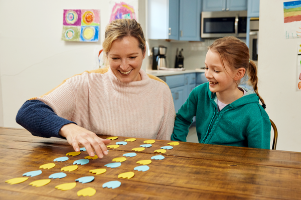 A parent and child make a flower garden with a pattern out of paper.