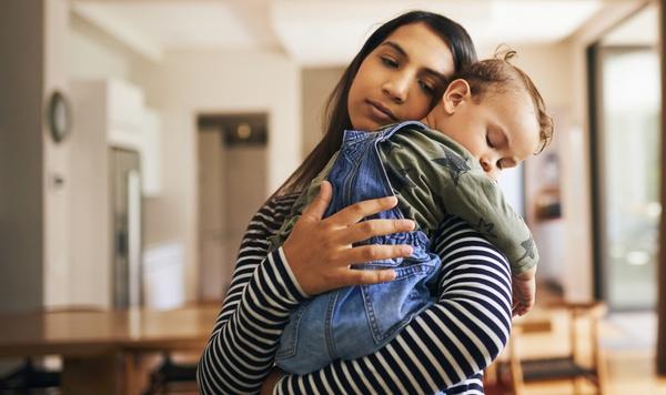 Mother holding toddler in her arms.