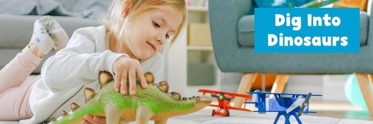 Young girl playing with toy dinosaur.