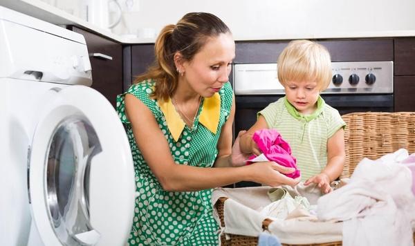 Young child helps mother with laundry.
