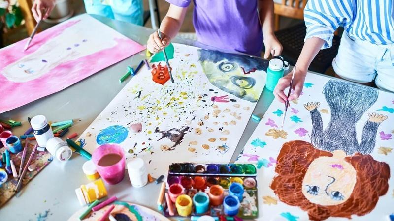 Image of children painting on large sheets of paper.