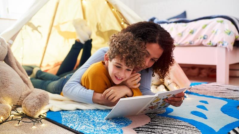 Mom and child reading together in a tent.