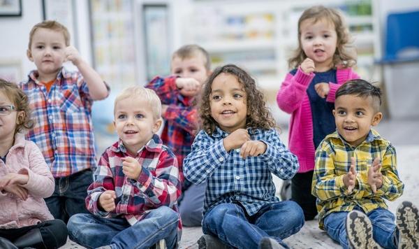 Image of preschoolers playing and doing hand motions to a song.