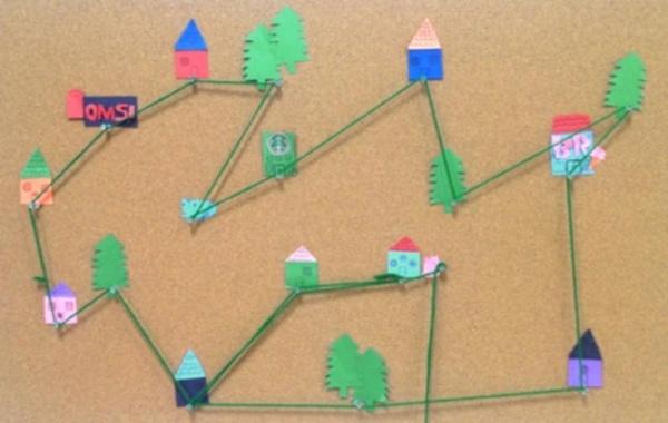 paper houses connected by a string trail on a cork board