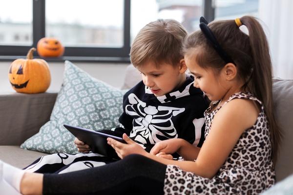 Two kids in Halloween costumes using a tablet.