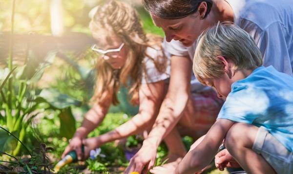 Imagen de una madre cuidando el jardín con su hija e hijo.