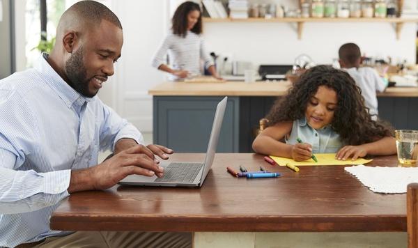 Father and daughter sitting at the kitchen table doing work and homework.