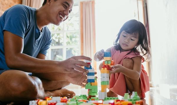 Father and daughter building towers out of blocks.
