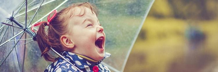 Young girl with umbrella playing in the rain.