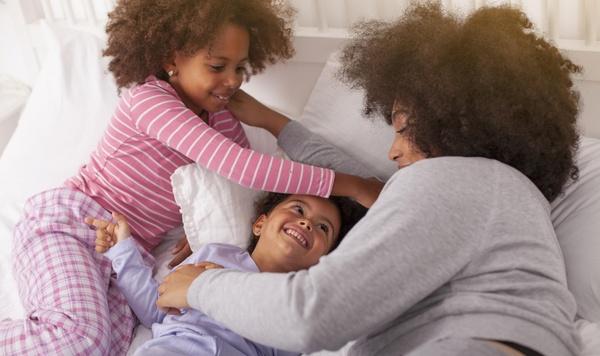Mother and two daughters snuggling in bed.