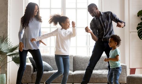 Image of family dancing in their living room together.