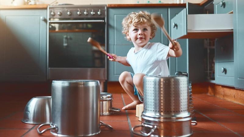 Image of young boy drumming on pots and pans.