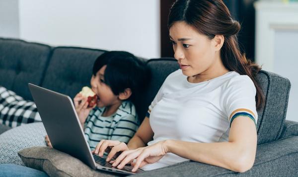 Image of mom working at home while her son watches television.