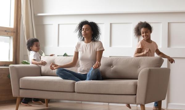 Image of mom meditating with kids playing.