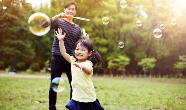 Image of father and daughter blowing bubbles.