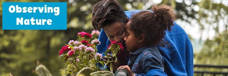 Image of mother and daughter smelling flowers.