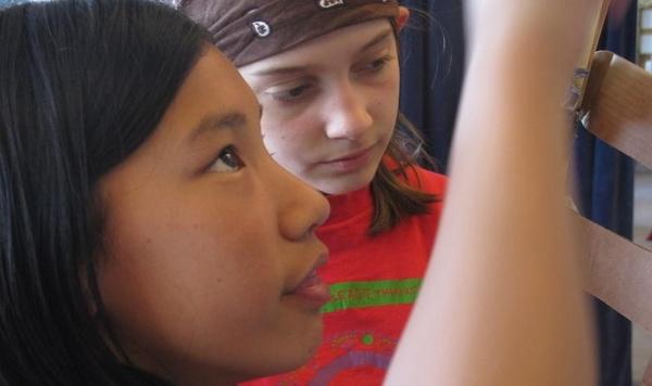 Close up of two girls looking at something they are building.
