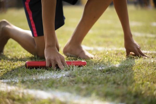 A child is behind a chalk line in a starting position and ready to start a relay race.