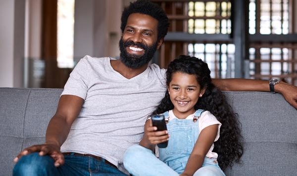 Father and daughter watching television on the couch.