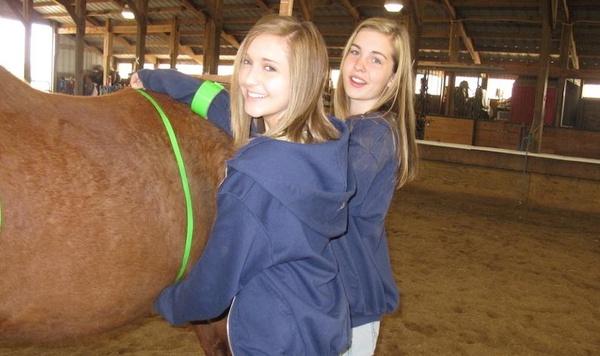 Two girls standing next to a horse.