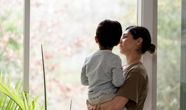 Mother holding young son and looking out the window.