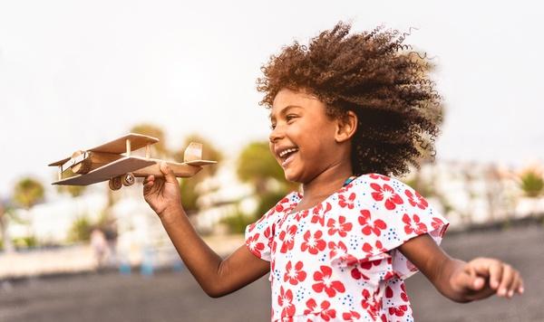 Young girl plays with a wooden airplane.