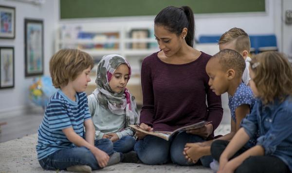 Teacher reading a book to children.